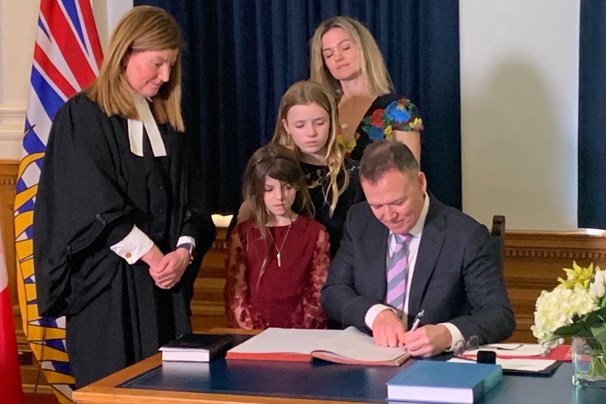 B.C. Liberal leader Kevin Falcon signs MLA book after taking the oath of office from clerk Kate Ryan-Lloyd (left), as his wife Jessica and daughters Rose and Josephine watch, at the B.C. legislature, May 16, 2022. (Tom Fletcher/Black Press)
