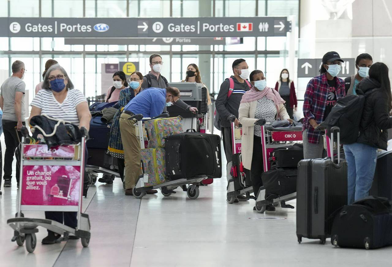 People wait in line to check in at Pearson International Airport in Toronto on Thursday, May 12, 2022.The Canadian Airports Council is asking the federal government to do away with COVID-19 protocols at customs to clear up the chaos that international travellers experience when they arrive in Canada. THE CANADIAN PRESS/Nathan Denette