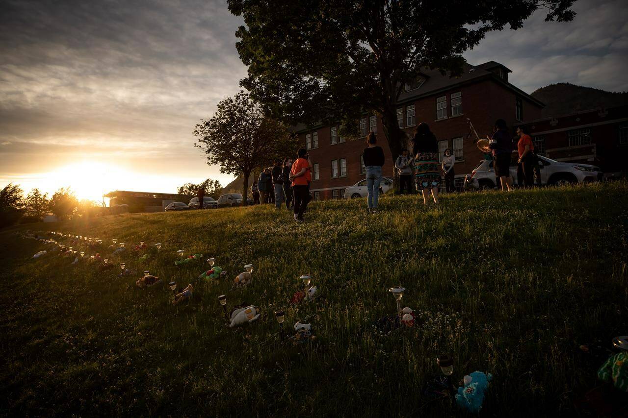 A group of youths lead a group drumming and singing at sunset outside the former Kamloops Indian Residential School, to honour the lives of those suspected to be buried in unmarked graves near the facility, in Kamloops, B.C., on Friday, June 4, 2021. THE CANADIAN PRESS/Darryl Dyck