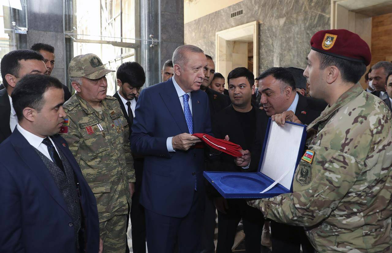 Turkish President Recep Tayyip Erdogan holds a national flag offered by Azerbaijani Turkish soldiers at the parliament, in Ankara, Turkey, Wednesday, May 18, 2022. Erdogan says NATO’s enlargement would depend on Finland and Sweden showing respect to Turkish sensitivities concerning terrorism, refusing to back down on his opposition to the two Nordic countries’ membership in the alliance because of their alleged support for Kurdish militants.(Turkish Presidency via AP Photo)