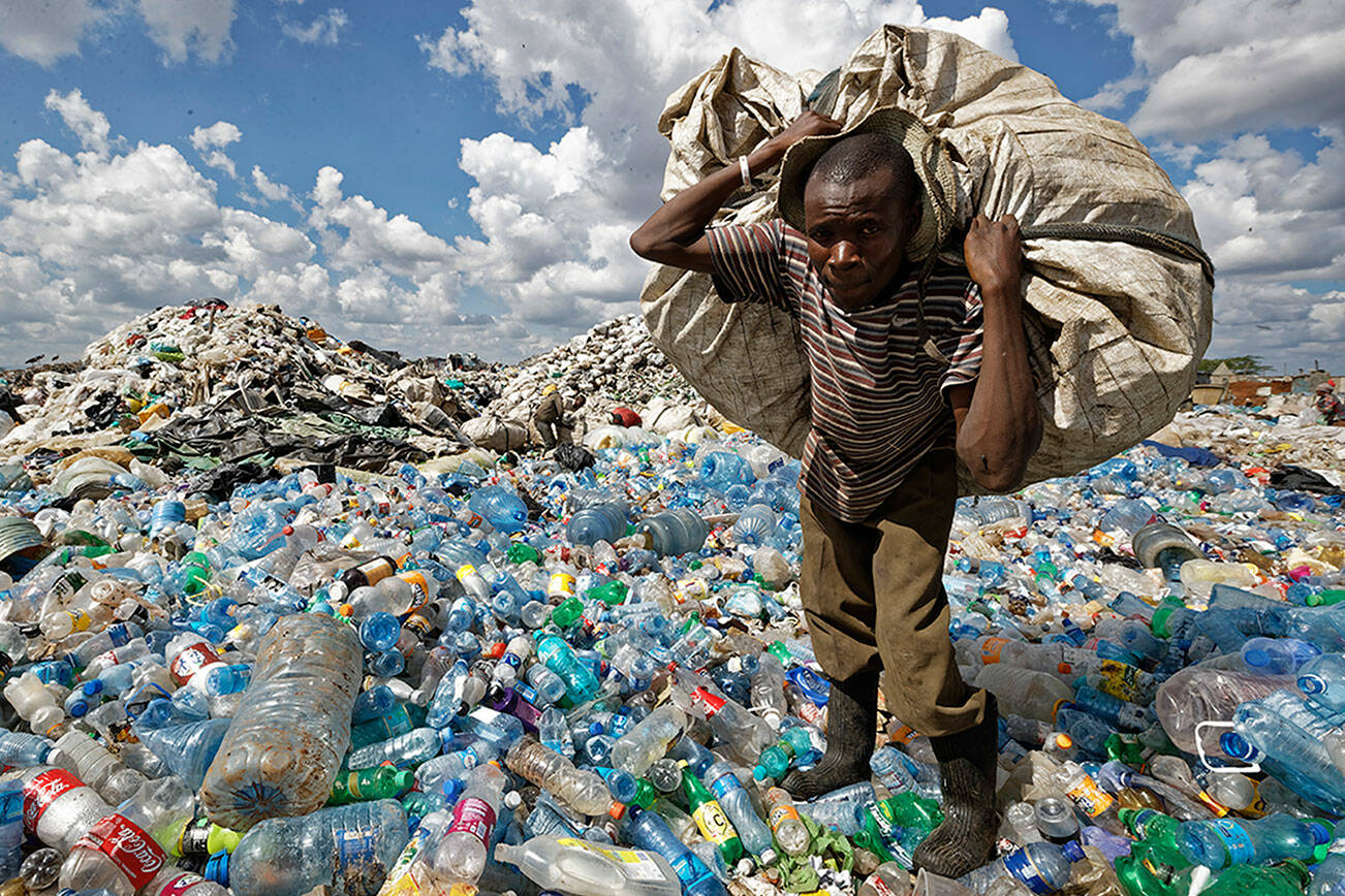 A man walks on a mountain of plastic bottles as he carries a sack of them to be sold for recycling after weighing them at the dump in the Dandora slum of Nairobi, Kenya on Dec. 5, 2018. The UN Environment Assembly unanimously voted in March to start to create a legally binding global treaty to address plastic pollution in the world’s oceans, rivers and landscape. (AP Photo/Ben Curtis, File)