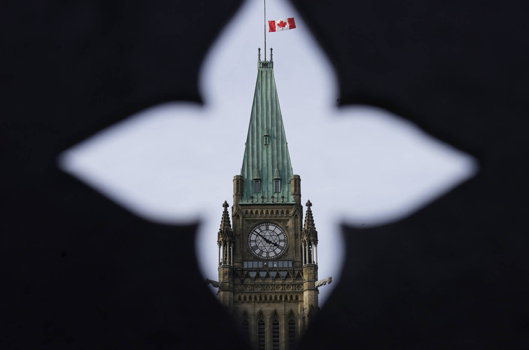 The Canadian flag flies at half mast over the Peace tower and parliament buildings Friday, Oct. 22, 2021.THE CANADIAN PRESS/Adrian Wyld