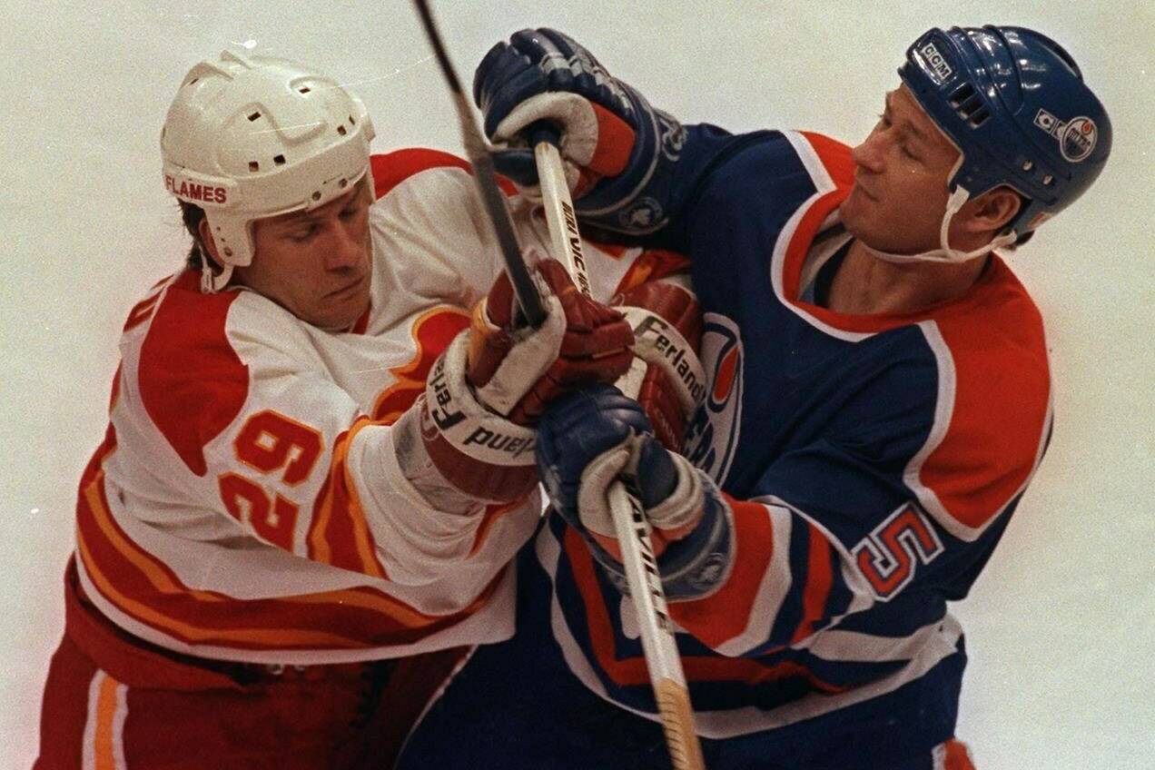 Calgary Flames’ Joel Otto (left) jousts with Edmonton Oilers’ Steve Smith during NHL playoff action in Calgary, Apr.16, 1991. (CP PICTURE ARCHIVE-Mike Ridewood)