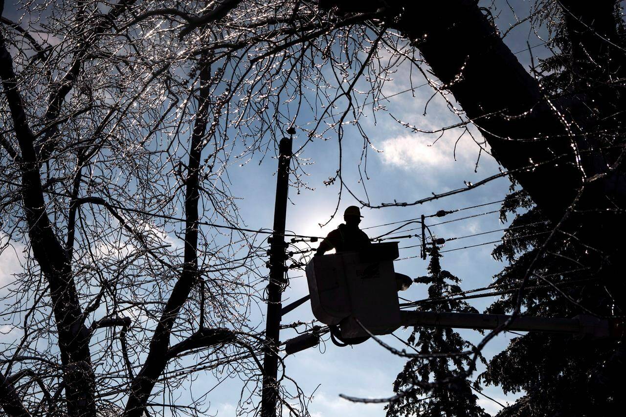 A Toronto Hydro line worker works to restore power to a house in Toronto, Friday, Dec. 27, 2013. A severe thunderstorm with high winds has created power outages across Ontario and led to at least four deaths. THE CANADIAN PRESS/Chris Young