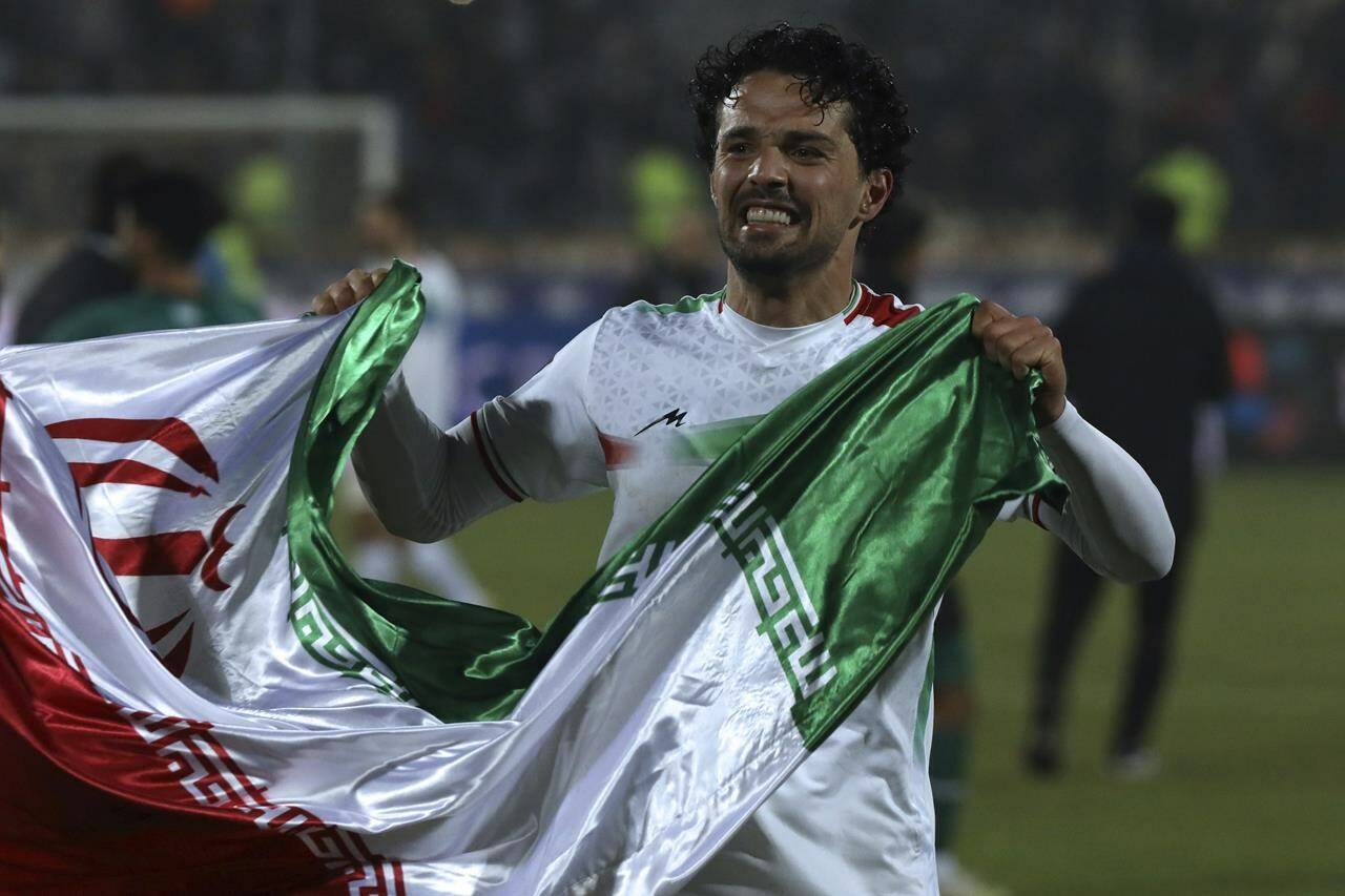 Iranian soccer player Omid Nor Afkan carries his national flag as he celebrates qualifying for 2022 World Cup after defeating Iraq, at the Azadi stadium in Tehran, Iran, on Jan. 27, 2022. Canada is set to host Iran in a friendly match in Vancouver on June 5, but controversy about the game has swirled. THE CANADIAN PRESS/AP-Vahid Salemi
