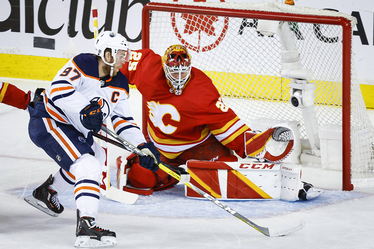 Edmonton Oilers centre Connor McDavid, left, tries to get the puck past Calgary Flames goalie Jacob Markstrom during first period NHL second-round playoff hockey action in Calgary, Thursday, May 26, 2022.THE CANADIAN PRESS/Jeff McIntosh