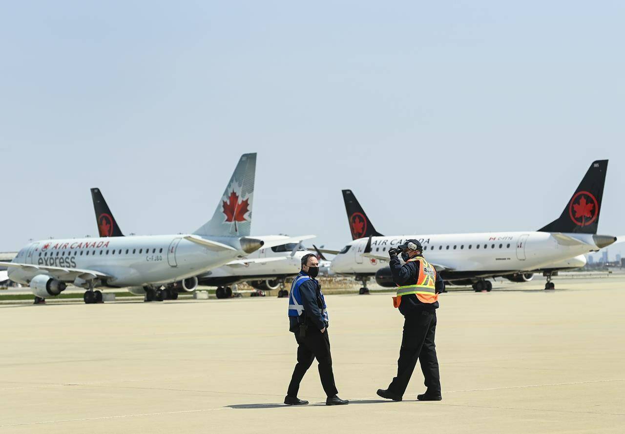 Airline ground crew walks past Air Canada planes as they sit on the tarmac at Pearson International Airport in Toronto on Tuesday, April 27, 2021. Tarmac delays on arriving flights skyrocket at Pearson airport. THE CANADIAN PRESS/Nathan Denette