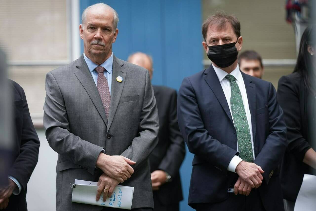 B.C. Premier John Horgan, left, and Health Minister Adrian Dix listen during an announcement to mark the start of construction on the redevelopment and modernization of the Burnaby Hospital, in Burnaby, B.C., on Monday, May 30, 2022. THE CANADIAN PRESS/Darryl Dyck