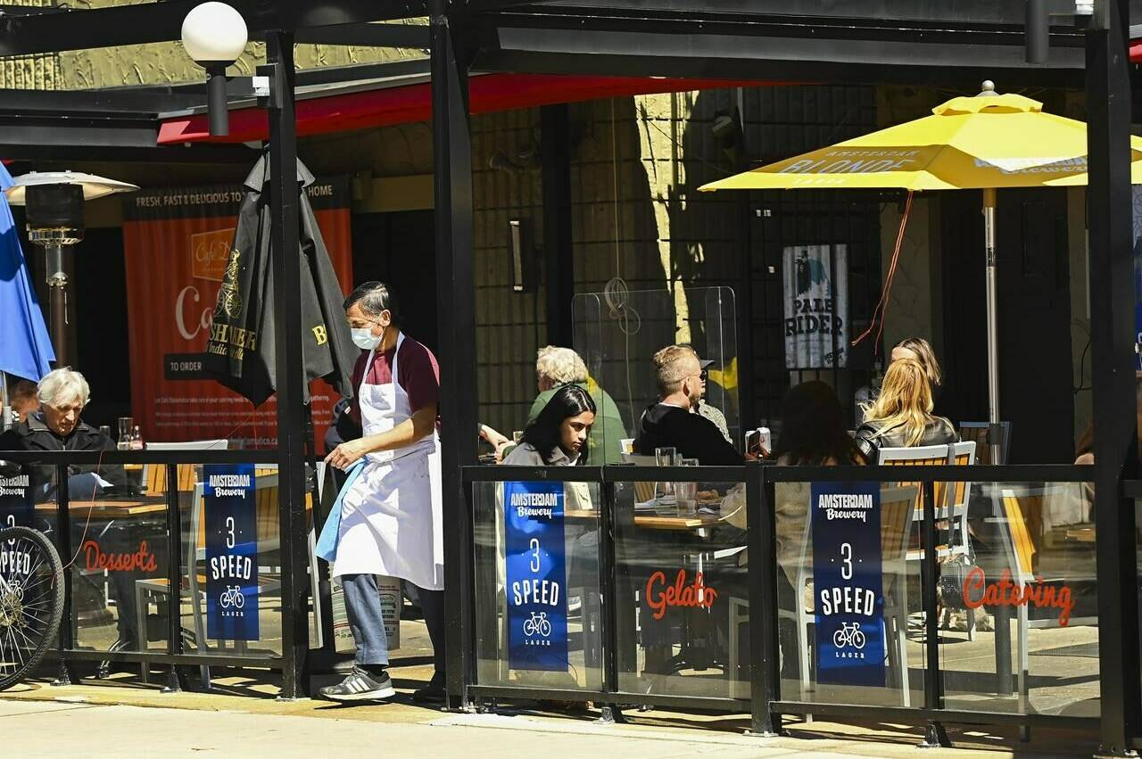 People sit on the outdoor patio at a restaurant in Little Italy during the COVID-19 pandemic in Toronto on Tuesday, March 30, 2021. Statistics Canada says restaurant and bar sales in March 2022 surpassed pre-pandemic levels. THE CANADIAN PRESS/Nathan Denette