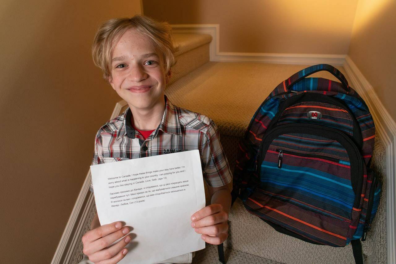 Yurii Kuzniak , 12, poses for a photo as he holds a note given to him from a 13-year-old Canadian boy in Edmonton on May 18, 2022. A backpack filled with games, toiletries and undergarments was gifted to him when his family arrived in Canada after fleeing Russia’s invasion of Ukraine. THE CANADIAN PRESS/Ryan Jackson