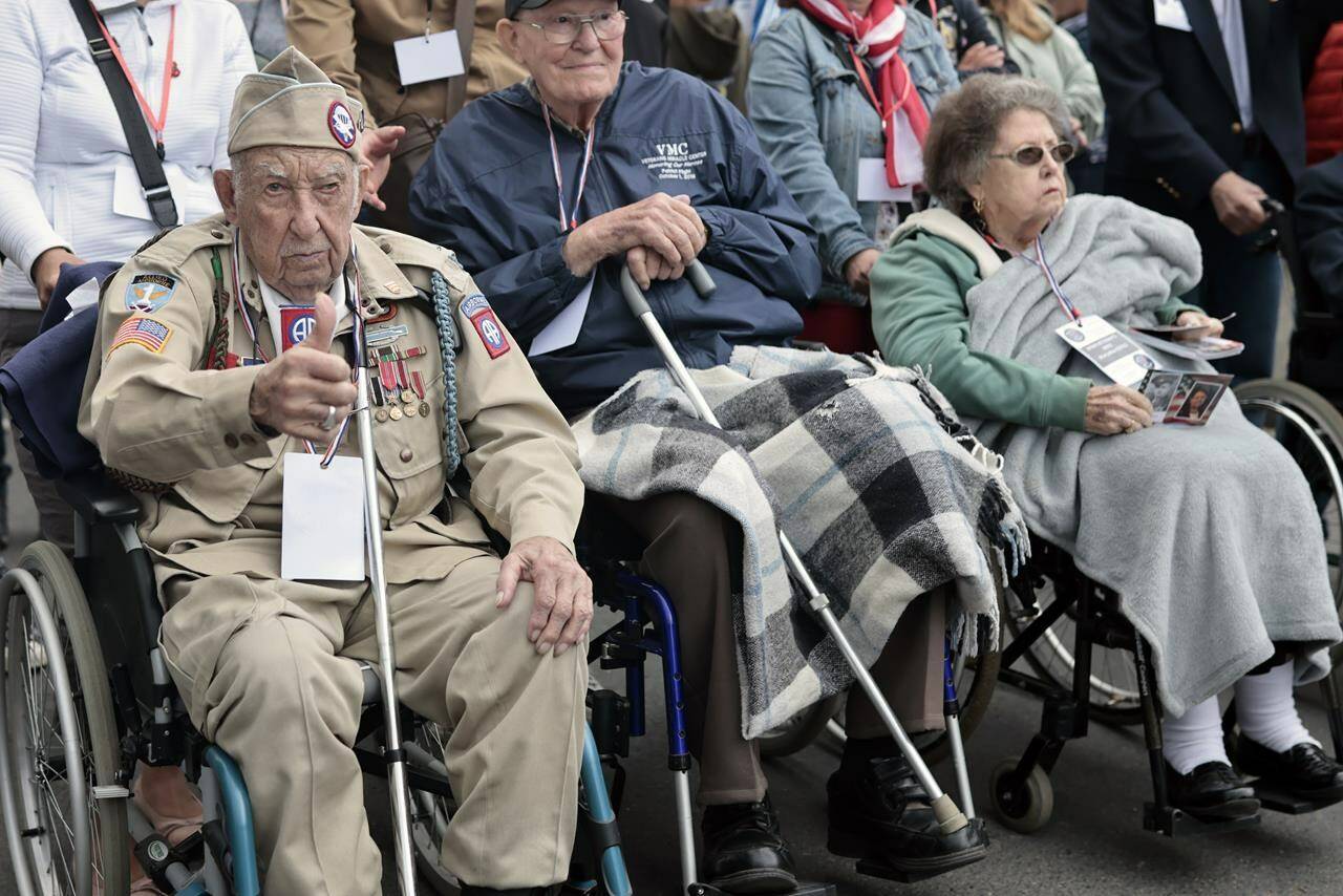 US WWII veteran Ray Wallace, of the 507th PIR 82rd Airborne, looks on as World War II history enthusiasts parade in WWII vehicles to commemorate the 78th anniversary of D-Day that led to the liberation of France and Europe from the German occupation, in Sainte-Mere-L’Eglise, Normandy, Sunday, June, 5, 2022. On Monday, the Normandy American Cemetery and Memorial, home to the gravesites of 9,386 who died fighting on D-Day and in the operations that followed, will host U.S. veterans and thousands of visitors in its first major public ceremony since 2019. (AP Photo/Jeremias Gonzalez)