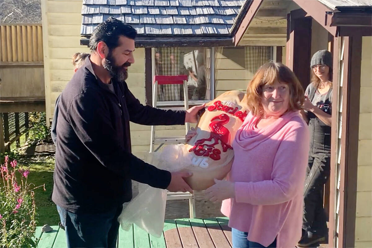 Tim Sangha, a member of the Nanaimo-based business partnership that has owned the Scarlet Ibis Pub and Restaurant since November 2020, presents a carving by woodcarver Rick Rotar of the Ibis business logo to Patricia Gwynne who owned and operated the Island’s most remote pub for more than 40 years. (Scarlet Ibis image)