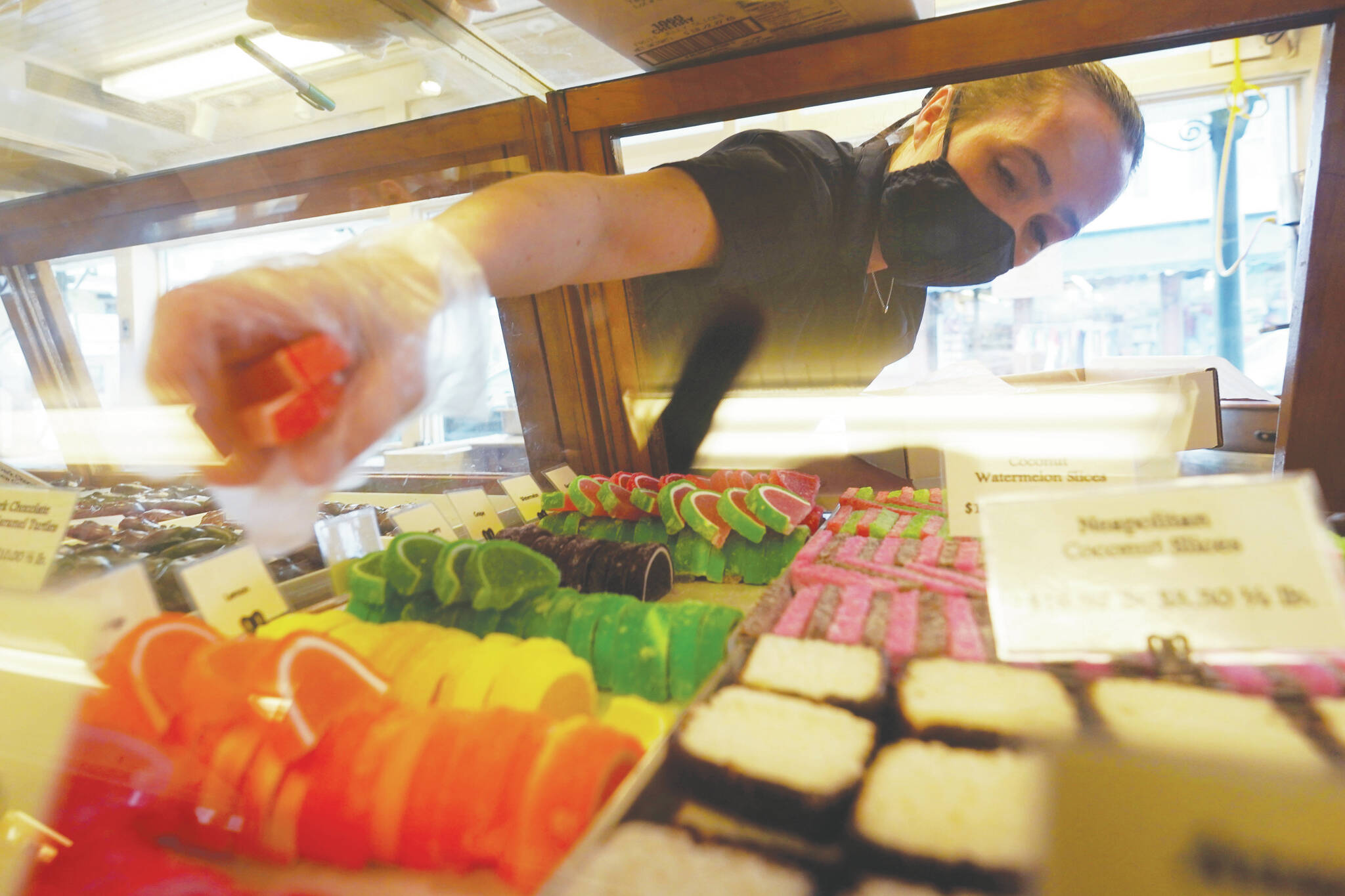 Beth Duckworth fills a display cabinet with sweet treats at The Goldenrod, a popular restaurant and candy shop, Wednesday, June 1, 2022, in York Beach, Maine. The business is looking to hire 30 to 40 more workers in addition to the 70 or so it now employs. (AP Photo/Robert F. Bukaty)