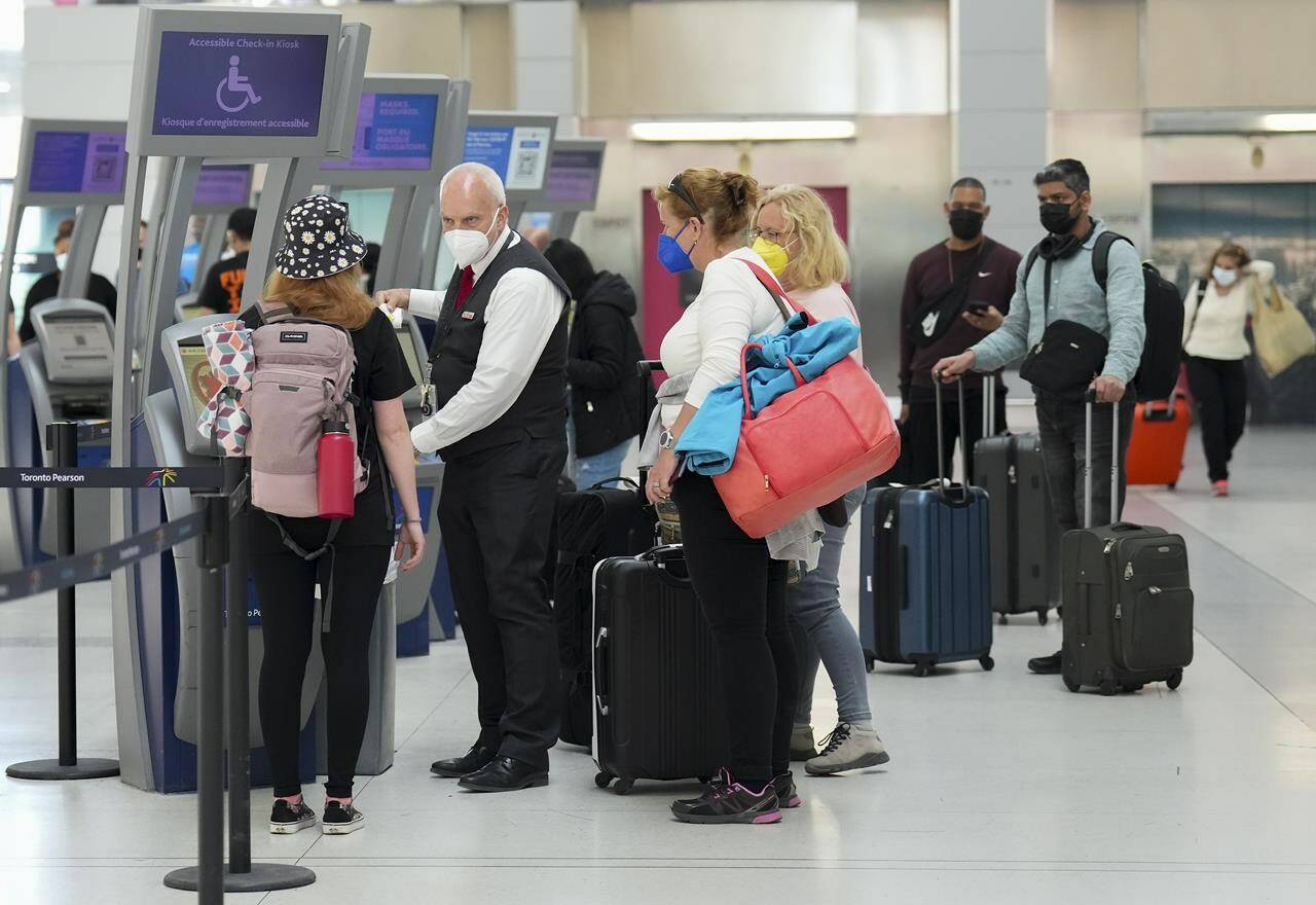 People wait in line to check in at Pearson International Airport in Toronto on Thursday, May 12, 2022. Sources confirm the federal government is putting an end to COVID-19 vaccine mandates for domestic and outbound international travellers and public sector workers. THE CANADIAN PRESS/Nathan Denette