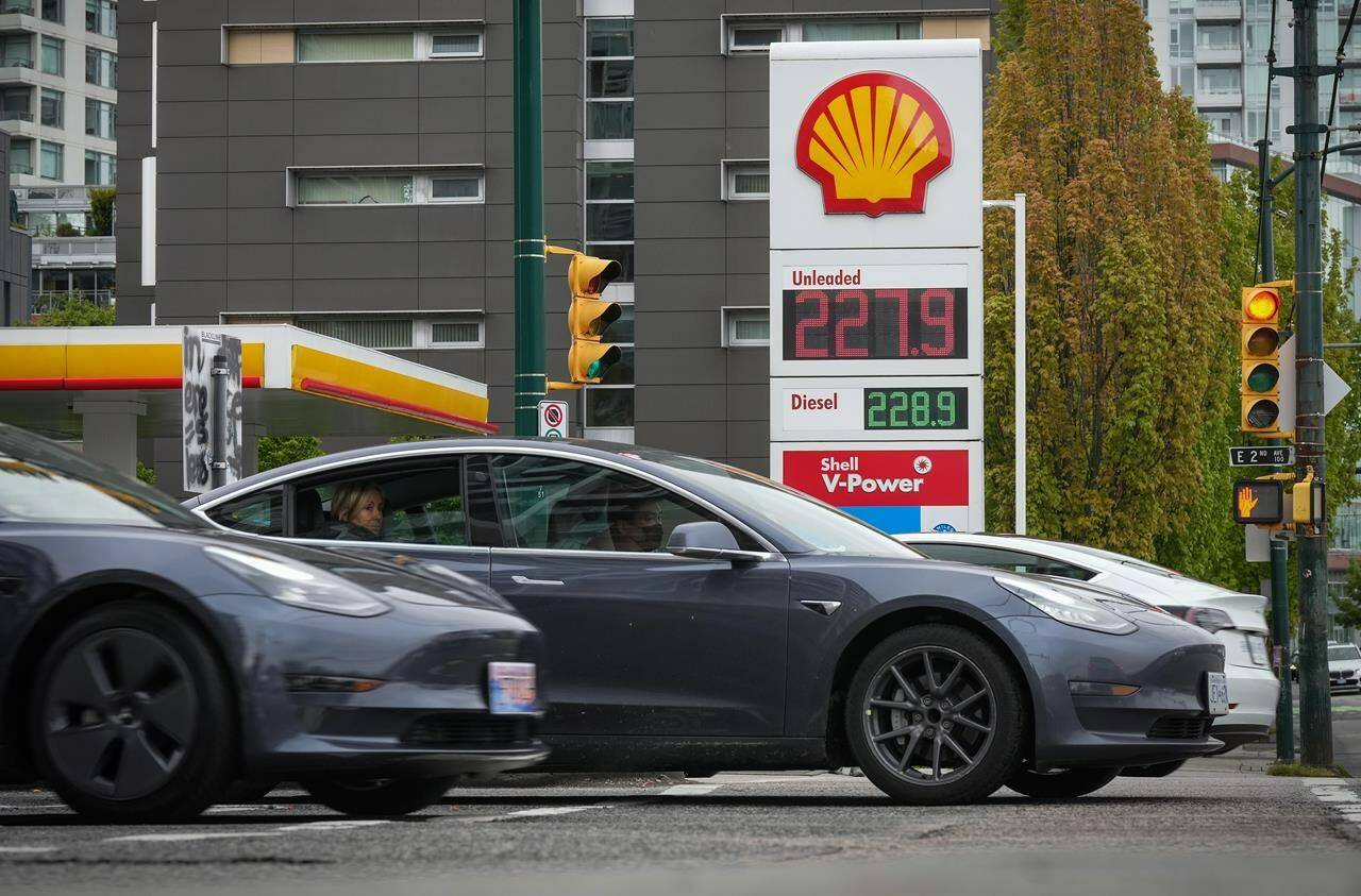 Tesla electric vehicles drive past a sign displaying the price of a litre of regular gasoline after it reached a new high of $2.28 in Vancouver on Saturday, May 14, 2022. THE CANADIAN PRESS/Darryl Dyck