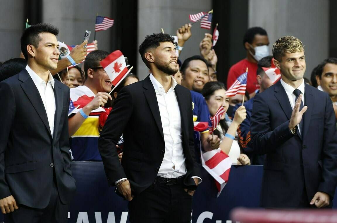International soccer players, from left, Hirving "Chucky" Lozano, Jonathan Osorio and Christian Pulisic wait along 6th Ave. for FIFA's announcement of the names of the host cities for the 2026 World Cup soccer tournament, Thursday, June 16, 2022, in New York. (AP Photo/Noah K. Murray)