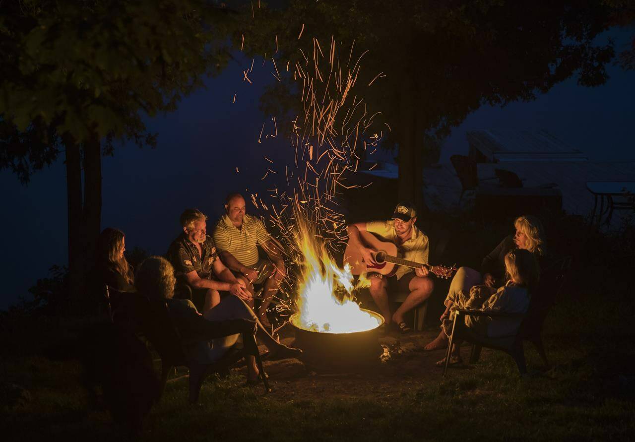 The Hanavan family and friends enjoy a camp fire on the shore of Shadow Lake near Coboconk, Ont., Saturday, Aug. 8, 2021. Though health restrictions have lifted, some summer camp operators say they’re grappling with staffing issues related to the COVID-19 pandemic. THE CANADIAN PRESS/Fred Thornhill