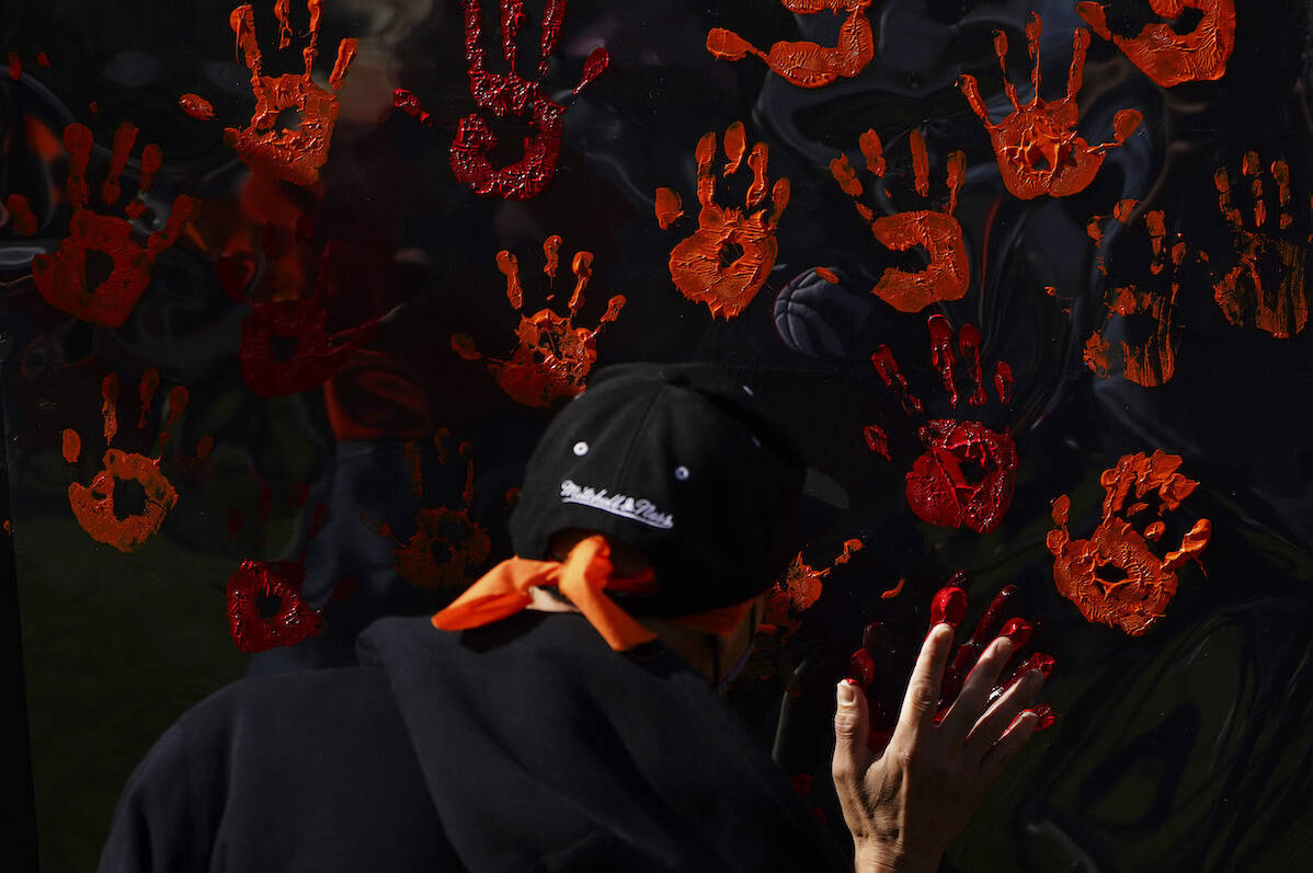 People contribute to a hand painting during the National Day for Truth and Reconciliation in Ottawa on Thursday, Sept. 30, 2021. THE CANADIAN PRESS/Sean Kilpatrick