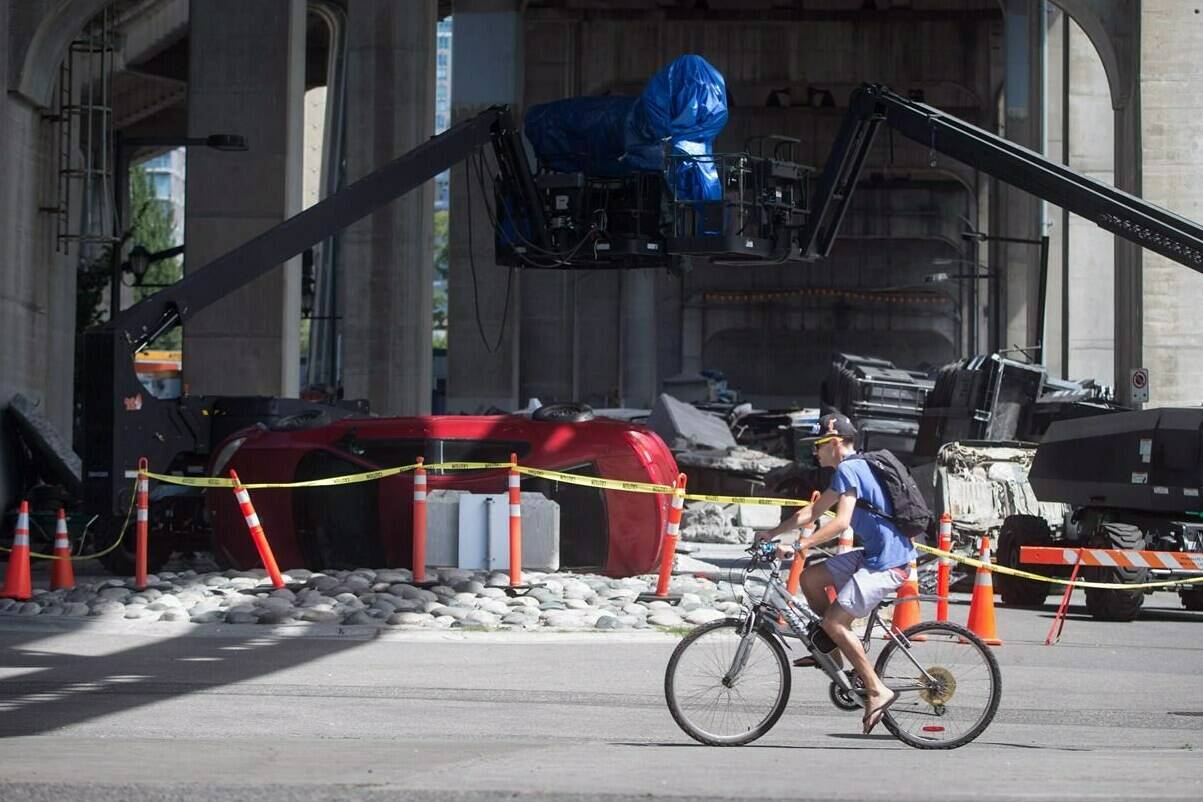 A cyclist rides past a film set for the movie “Deadpool 2” in Vancouver, B.C., Tuesday, Aug. 15, 2017. A 15-month dispute in British Columbia’s film and television industry has ended with the ratification of a new contract for creative and logistical people working on productions shot in the province. THE CANADIAN PRESS/Darryl Dyck