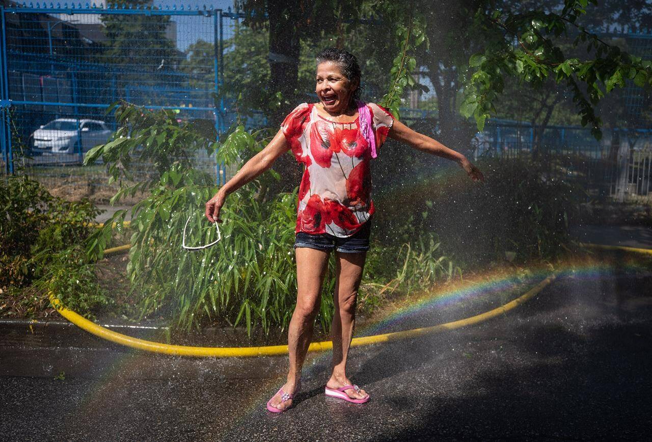 Pinky, who asked to be identified only by her first name, reacts as she cools off in the water at a temporary misting station in the Downtown Eastside of Vancouver, B.C., on Monday, June 28, 2021.Environment Canada says heat warnings will persist in British Columbia and Yukon for at least another day, but cooler conditions are on the way. THE CANADIAN PRESS/Darryl Dyck