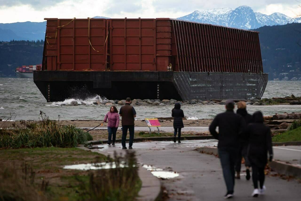 A barge that drifted loose on English Bay sits grounded on rocks during a massive windstorm, in Vancouver, B.C., Monday, Nov. 15, 2021. A timeline has finally been announced for the removal of a huge barge that wedged itself onto a beach in Vancouver’s English Bay last November. THE CANADIAN PRESS/Darryl Dyck