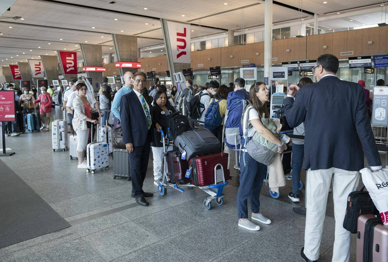 Passengers lineup at the check in counter at Pierre Elliott Trudeau airport, in Montreal, Wednesday, June 29, 2022. An analytics firm says a majority of domestic flights to some of Canada’s busiest airports were delayed or cancelled over the past week. THE CANADIAN PRESS/Ryan Remiorz