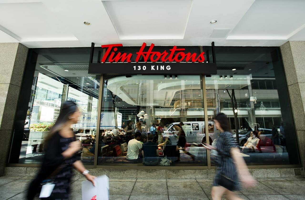 People walk past a newly-renovated Tim Hortons in Toronto, Thursday, July 25, 2019. Tim Hortons has joined a growing list of corporations pulling financial support for Hockey Canada in the wake of the federation’s handling of an alleged sexual assault. THE CANADIAN PRESS/Nathan Denette