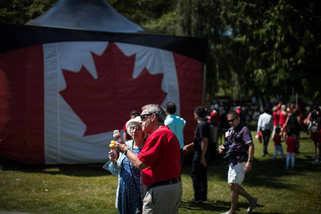 An elderly couple eat ice cream cones near a large Canadian flag during Canada Day festivities in West Vancouver on Monday, July 1, 2019. It’s a long weekend that ushers in the unofficial start of summer with potato salad and grilled food, popsicles and lemonade, swimming and fireworks. Yet Canada Day entertaining will come with a bigger price tag this year as inflation surged to its highest level in nearly 40 years, Statistics Canada said. THE CANADIAN PRESS/Darryl Dyck