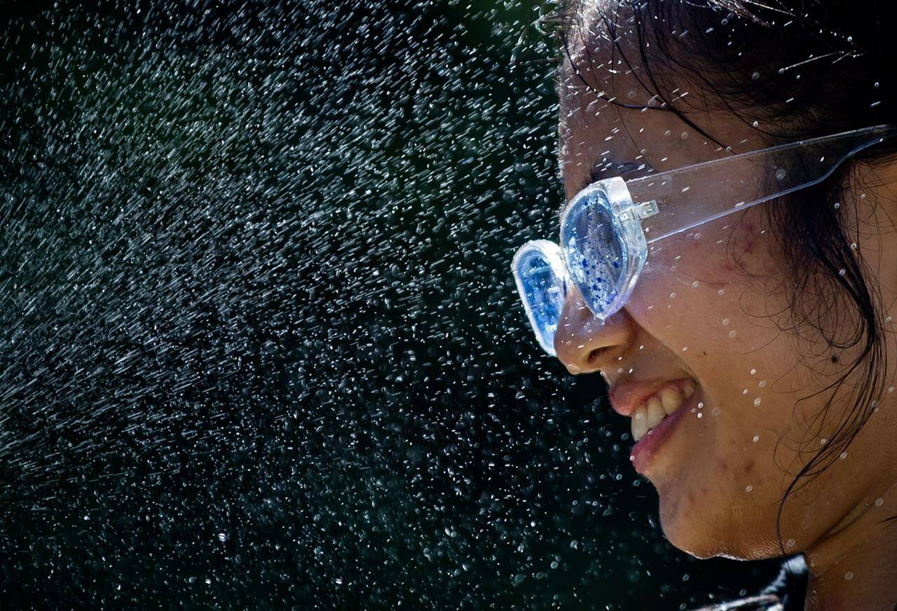 Leanne Opuyes uses a spray bottle to mist her face while cooling off in the frigid Lynn Creek water in North Vancouver, B.C., on Monday, June 28, 2021. Heat warnings and special weather statements cover much of Yukon from the northwest to the southeast and Environment Canada says residents in the territory can’t expect much relief until at least mid-week. THE CANADIAN PRESS/Darryl Dyck