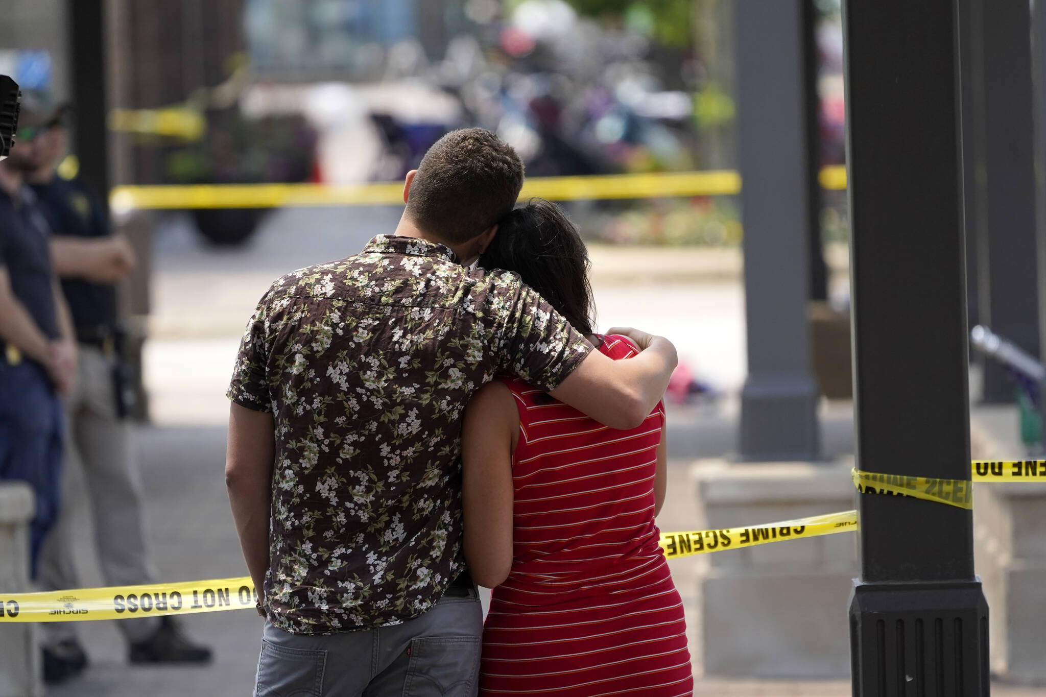 Brooke and Matt Strauss, who were married Sunday, look toward the scene of the mass shooting in downtown Highland Park, Ill., a Chicago suburb, after leaving their wedding bouquets near the scene of Monday’s mass shooting, Tuesday, July 5, 2022. (AP Photo/Charles Rex Arbogast)