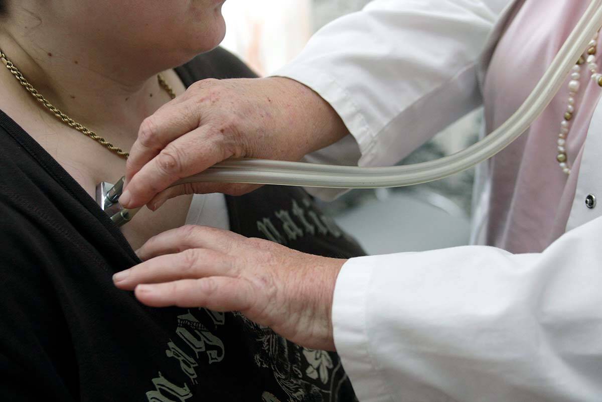 A doctor examines a patient with a stethoscope in her doctor’s office. In B.C., some family doctors are calling for a switch from the current payment model that compensates them per patient, to one that compensates them regardless of the time they spend with each person. CANADIAN PRESS/AP/Thomas Kienzle