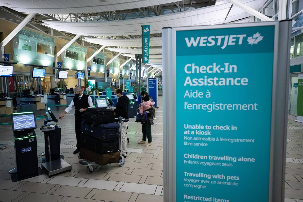 WestJet Airlines says a system outage Thursday morning is delaying some flights and intermittently impacting the company’s operations. A Westjet employee assists people checking in for a domestic flight at Vancouver International Airport, in Richmond, B.C., on Thursday, January 21, 2021. THE CANADIAN PRESS/Darryl Dyck