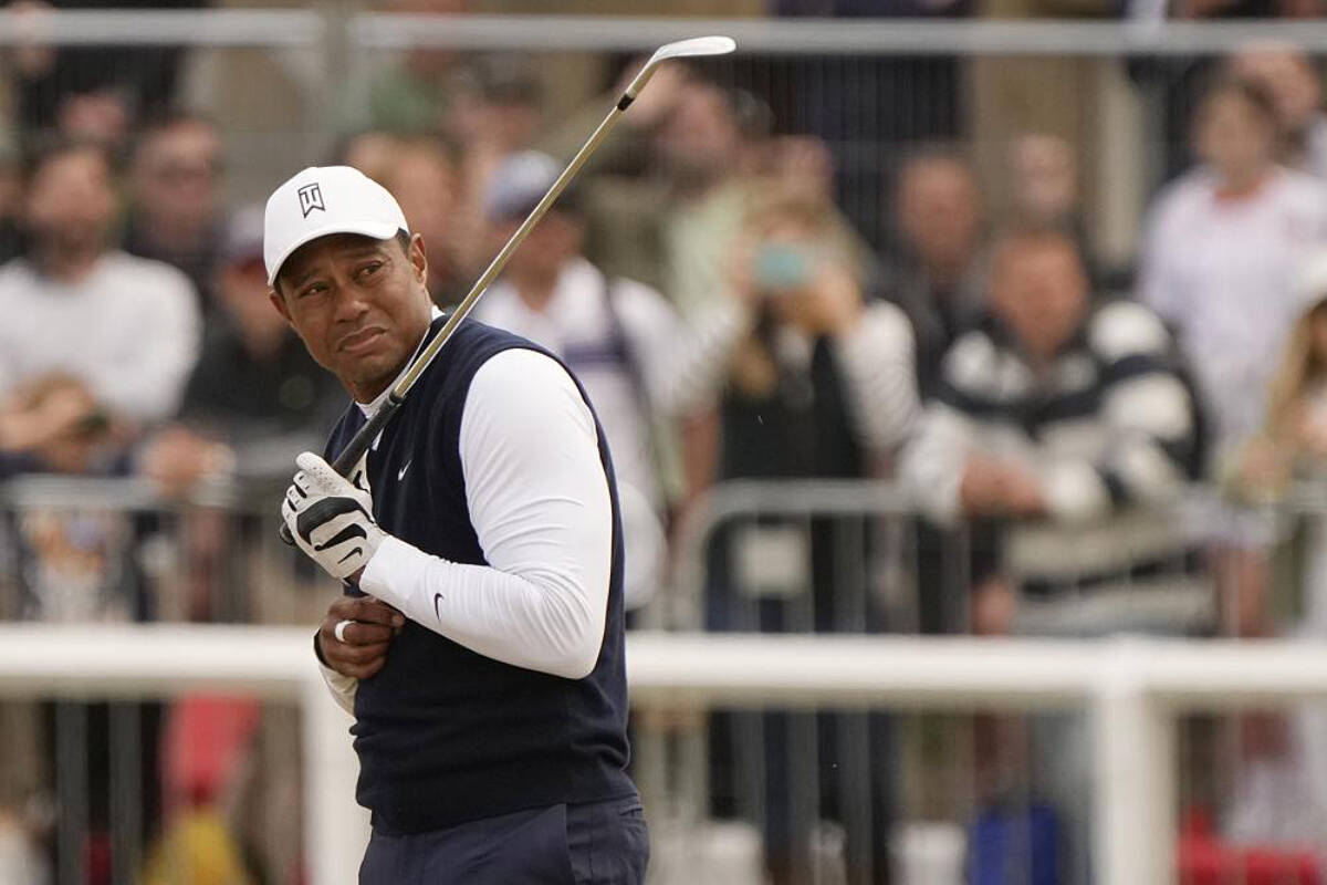 Tiger Woods of the US reacts to dust after playing a shot on the 1st hole during the first round of the British Open golf championship on the Old Course at St. Andrews, Scotland, Thursday, July 14 2022. The Open Championship returns to the home of golf on July 14-17, 2022, to celebrate the 150th edition of the sport’s oldest championship, which dates to 1860 and was first played at St. Andrews in 1873. (AP Photo/Gerald Herbert)