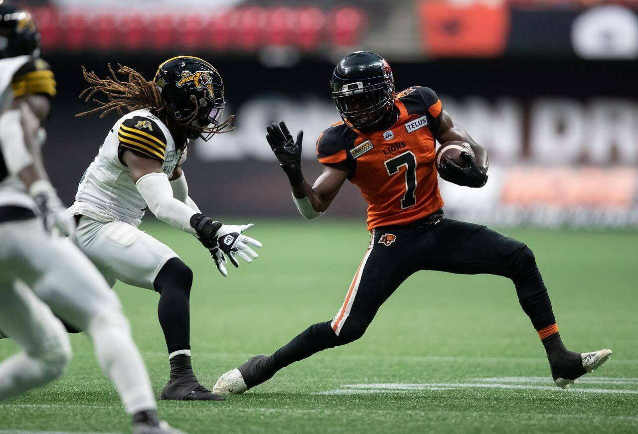 B.C. Lions’ Lucky Whitehead (7) tries to run the ball past Hamilton Tiger-Cats’ Tunde Adeleke during the first half of CFL football game in Vancouver, on Thursday, July 21, 2022. THE CANADIAN PRESS/Darryl Dyck