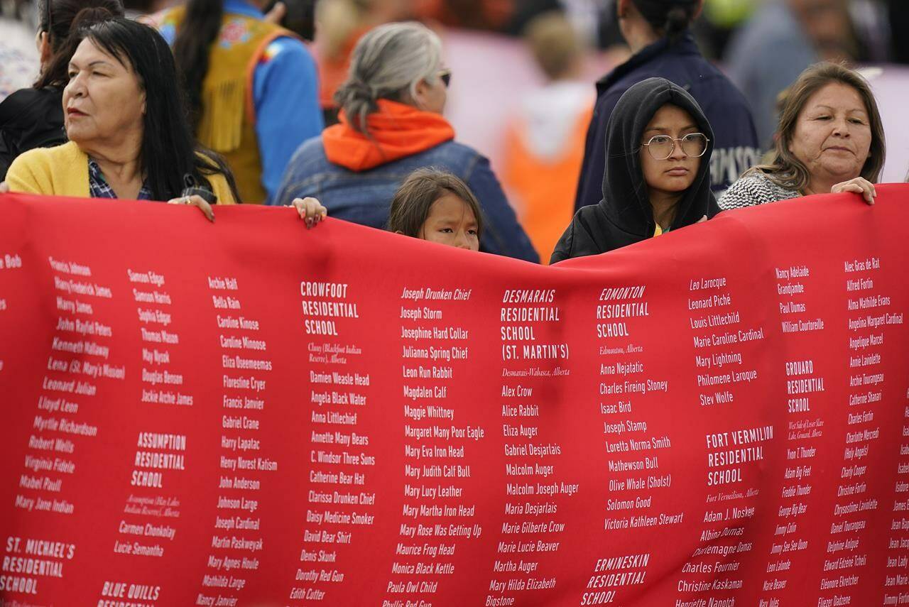 Indigenous people hold up a banner while waiting for Pope Francis during his visit to Maskwaci, the former Ermineskin Residential School, Monday, July 25, 2022, in Maskwacis, Alberta. Pope Francis traveled to Canada to apologize to Indigenous peoples for the abuses committed by Catholic missionaries in the country’s notorious residential schools. (AP Photo/Eric Gay)