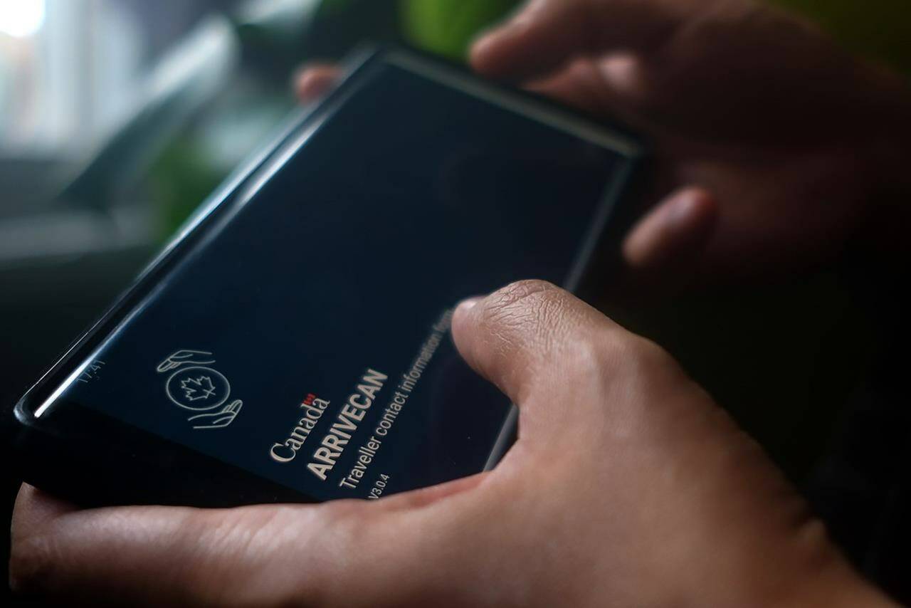 A person holds a smartphone set to the opening screen of the ArriveCan app in a photo illustration made in Toronto, Wednesday, June 29, 2022. The app continues to stir up division, wearing on the patience of doctors, border officers, governance experts and some travellers in the wake of a glitch that confused thousands of passengers.THE CANADIAN PRESS/Giordano Ciampini