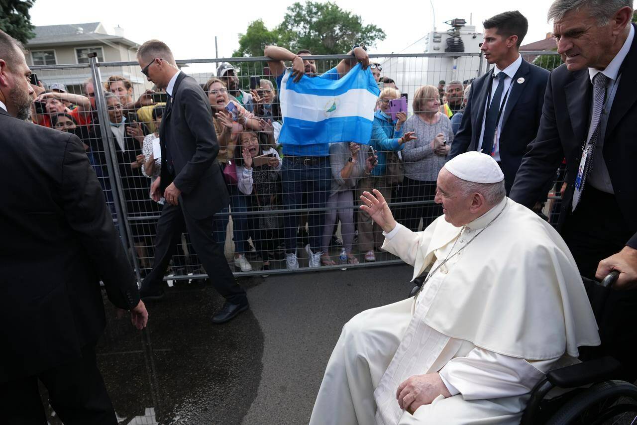 A person holds the flag of Argentina as Pope Francis greets the public following a service at the Sacred Heart Church of the First Peoples in Edmonton on Monday, July 25, 2022, as part of his papal visit across Canada. THE CANADIAN PRESS/Nathan Denette