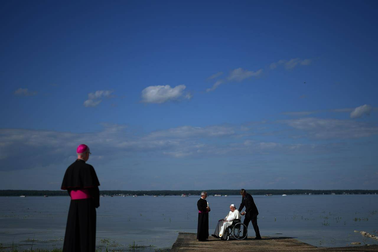 Pope Francis gets water from the lake after blessing it during the annual pilgrimage event in Lac Ste. Anne, Alta., Tuesday, July 26, 2022. THE CANADIAN PRESS/Nathan Denette