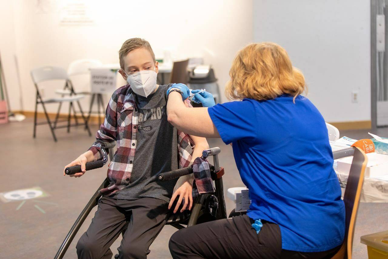 Riley Oldford, 16-years-old and who suffers from cerebral palsy, is the first N.W.T. youth to get the Pfizer vaccine, receives the needle from Nurse practitioner Janie Neudorf in Yellowknife on Thursday May 6, 2021. THE CANADIAN PRESS/Bill Braden