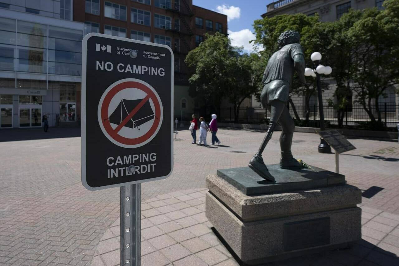 A federal sign indicates "No Camping" in a downtown square next to the Terry Fox statue across from the Parliament buildings, Wednesday, July 27, 2022 in Ottawa. THE CANADIAN PRESS/Adrian Wyld