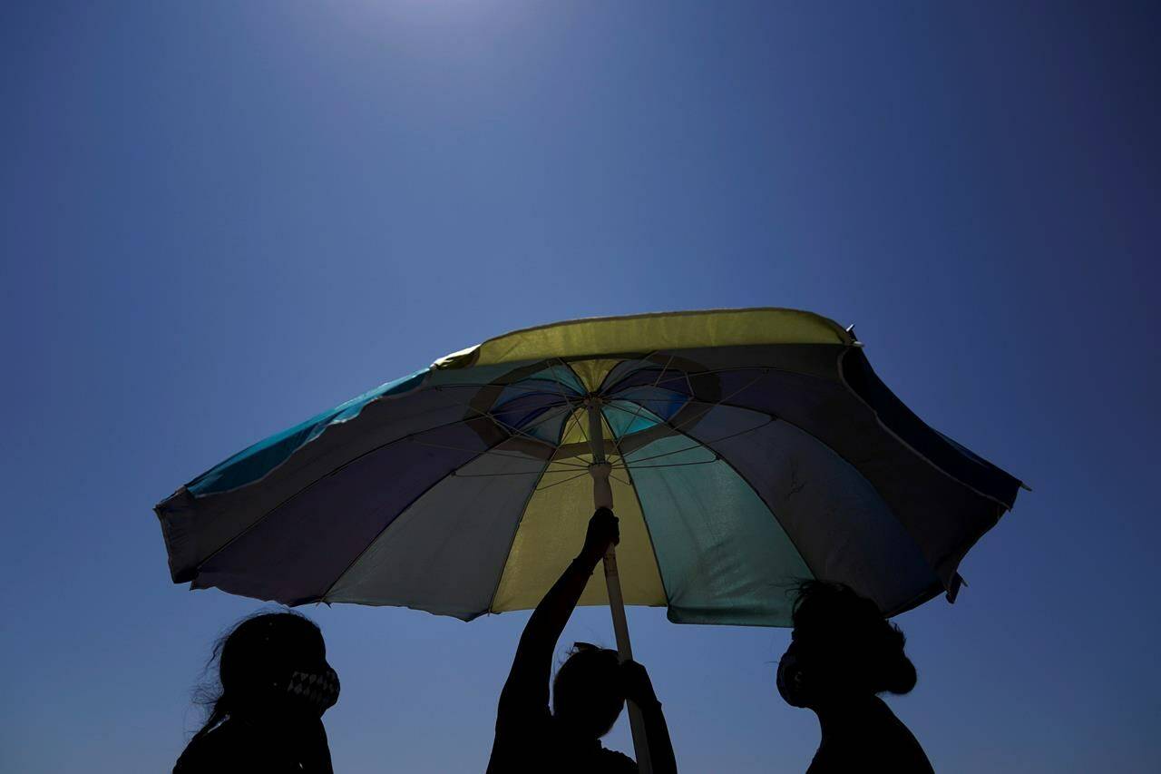 Beachgoers set up an umbrella on the beach in Huntington Beach, Calif., Saturday, Sept. 5, 2020. A study by Toronto researchers says the prevalence of non-melanoma skin cancer is on the rise in Ontario, climbing by 30 per cent from 2003 to 2017 following a period of decline decades earlier. THE CANADIAN PRESS/AP/Jae C. Hong