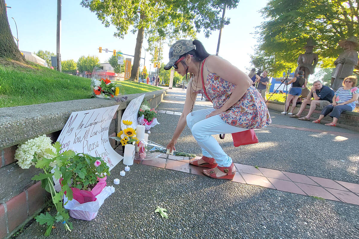 A woman laid a wreath of flowers at a Tuesday night (July 26) vigil for the victims of the Langley shootings at Innes Corners Plaza in Langley City. Around 100people turned out. (Dan Ferguson/Langley Advance Times)