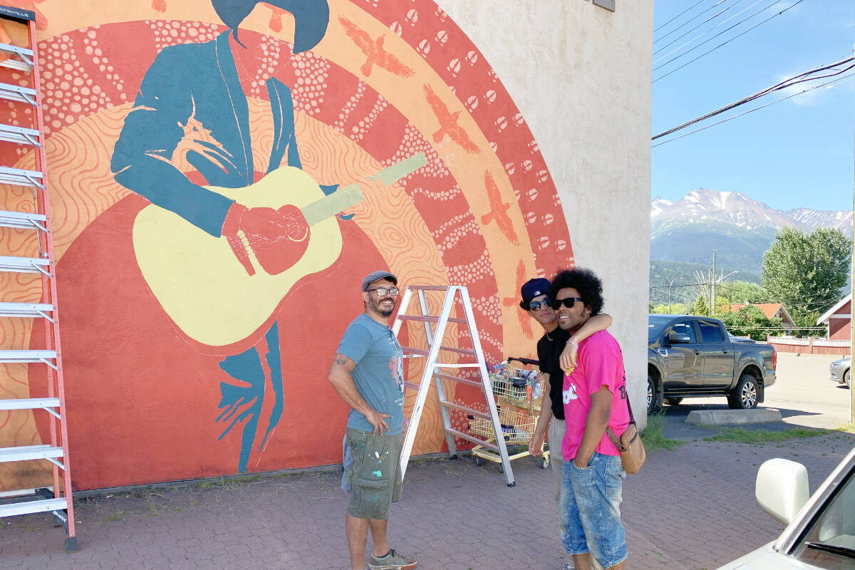 Grammy Award-winner Alex Cuba and his son Owen chat with Facundo Gastiazoro in front of the artist’s in-progress mural of Cuba on the side of the Warehouse One building. (Grant Harris photo)
