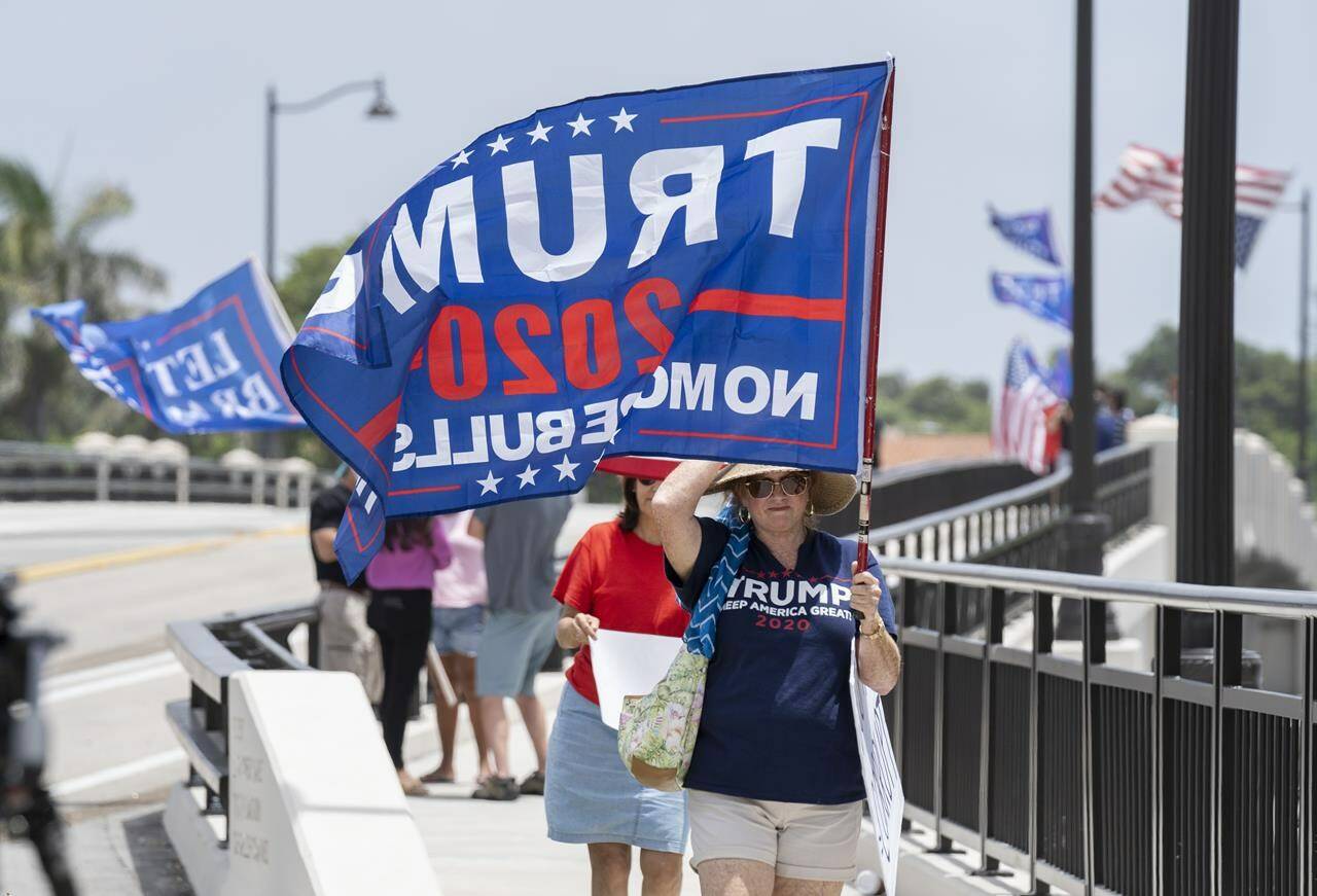 Trump supporters carry flags near Mar-a-Lago in Palm Beach, Fla., on Tuesday, August 9, 2022. (Greg Lovett/The Palm Beach Post via AP)