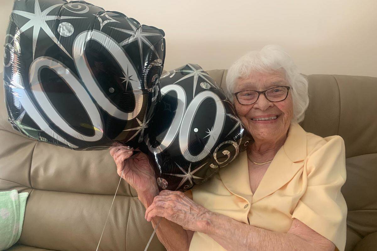 Jane Gagnon holds up balloons left over from celebrating her 100th birthday Aug. 14, 2022 (Brittany Webster - Black Press)