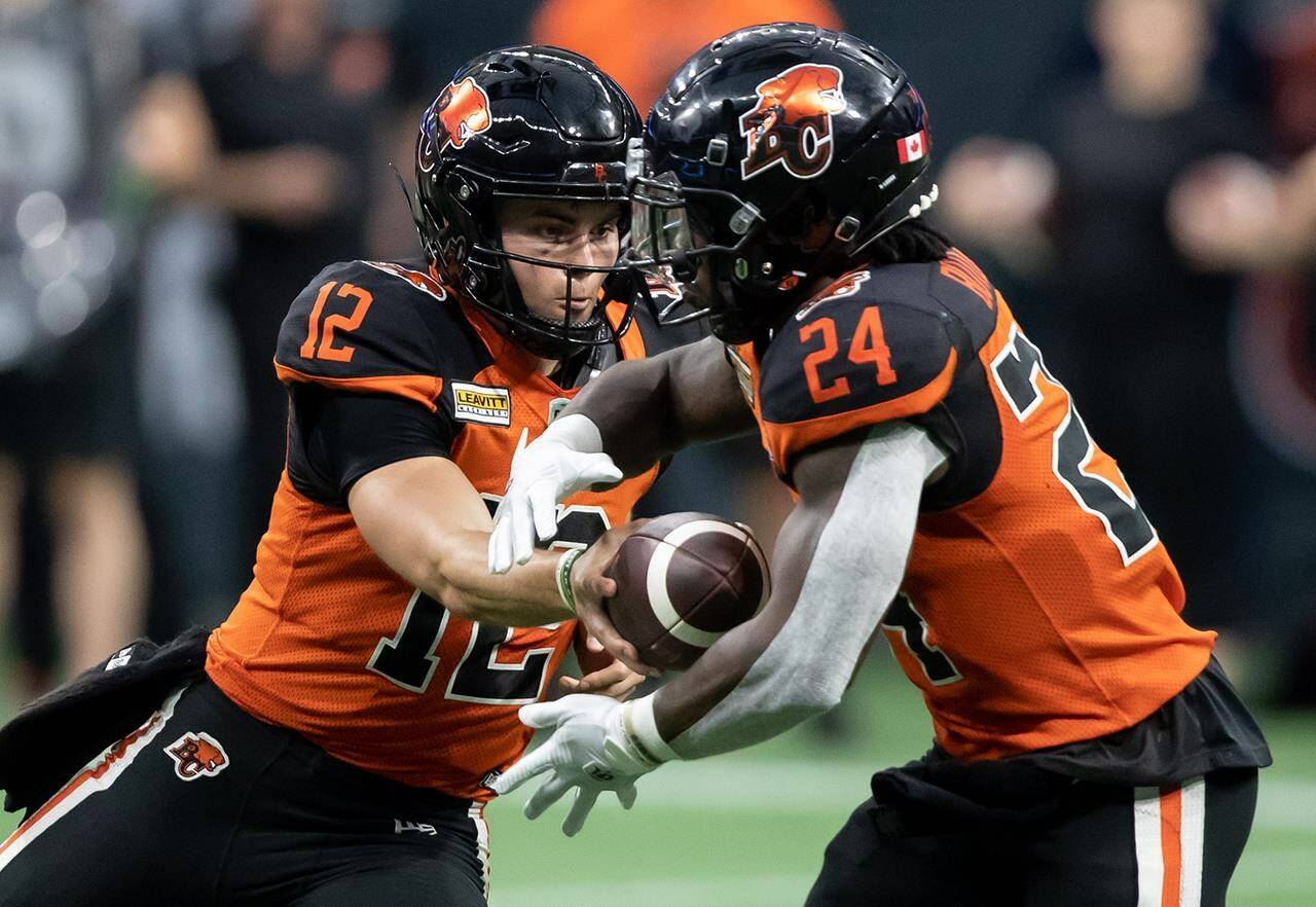 B.C. Lions quarterback Nathan Rourke (12) hands off to James Butler (24) during the first half of CFL football game against the Hamilton Tiger-Cats in Vancouver, on Thursday, July 21, 2022. THE CANADIAN PRESS/Darryl Dyck