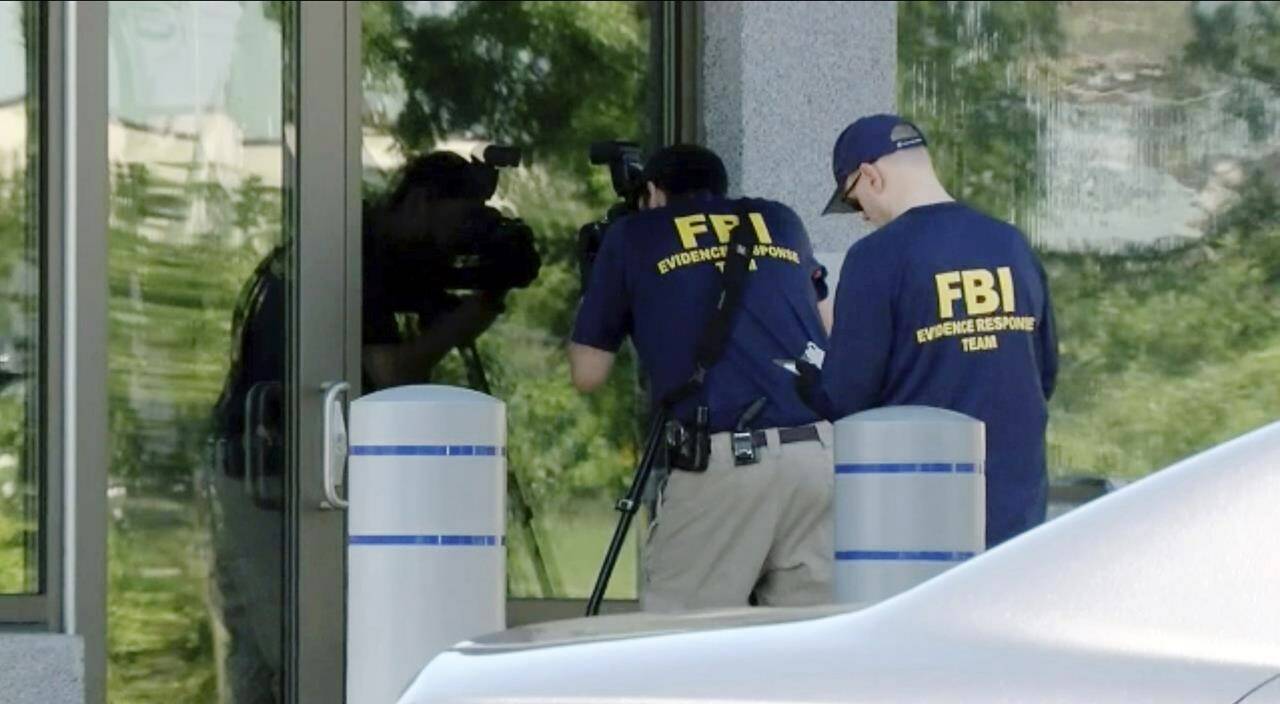 In this still image taken from WKEF/WRGT video, members of the FBI Evidence Response Team work outside the FBI building in Kenwood, Ohio, Thursday, Aug. 11, 2022. An armed man decked out in body armor tried to breach a security screening area at an FBI field office in Ohio on Thursday, then fled and was injured in an exchange of gunfire in a standoff with law enforcement, authorities said. (Courtesy WKEF/WRGT via AP)