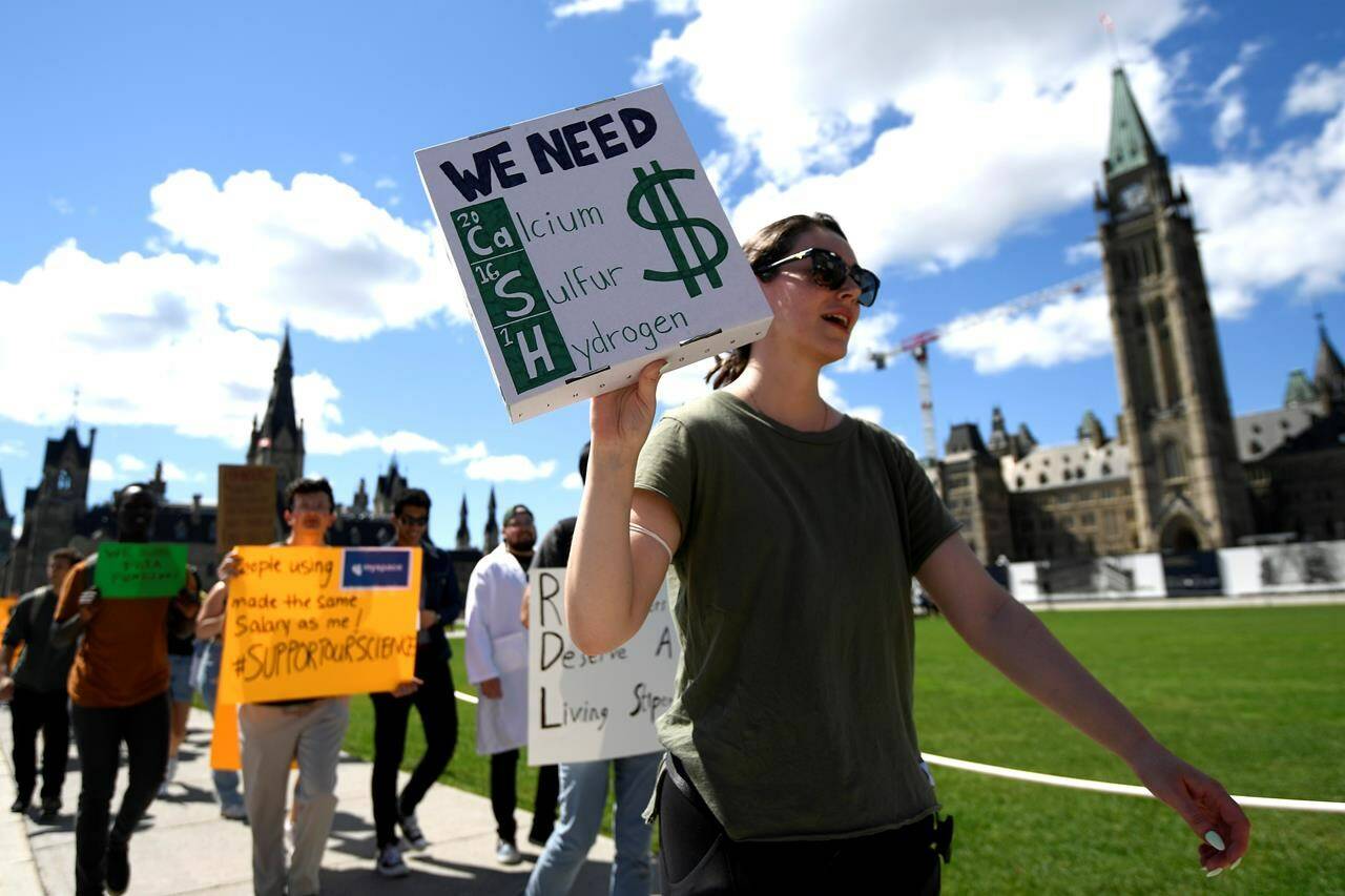 Scientists and researchers rally on Parliament Hill to call on the federal government to increase funding for graduate and post-doctoral scholars, during the “Support Our Science” rally on Parliament Hill in Ottawa, on Thursday, Aug. 11, 2022. THE CANADIAN PRESS/Justin Tang