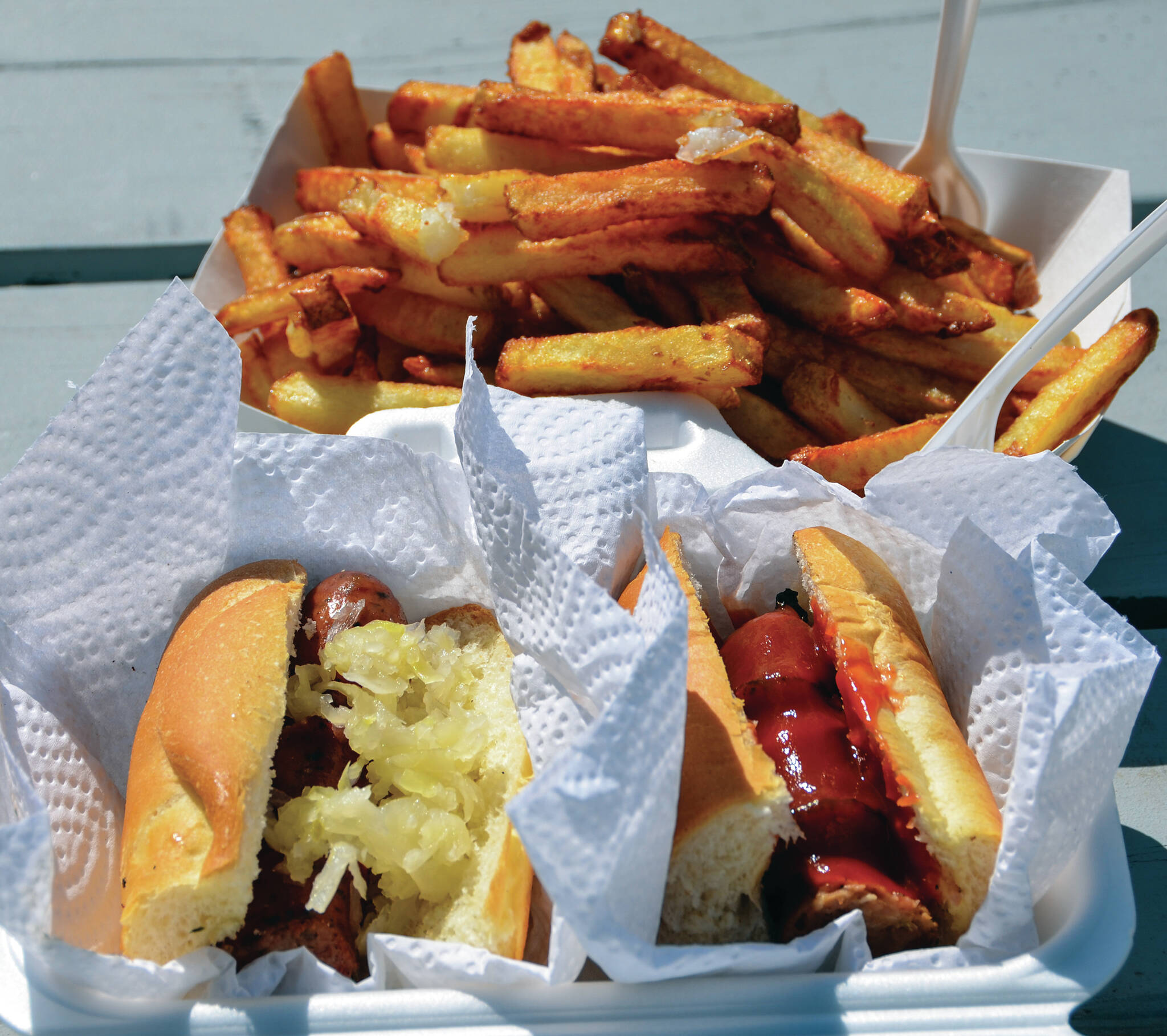 Left, a speciality Bulgarian sausage slavered in sauerkraut, right, a beef sausage with requisite ketchup, crowned by a generous serving of fries are among the many summertime food varieties. Ketchup, a popular condiment, has not always been made with tomatoes.. (Black Press file photo)