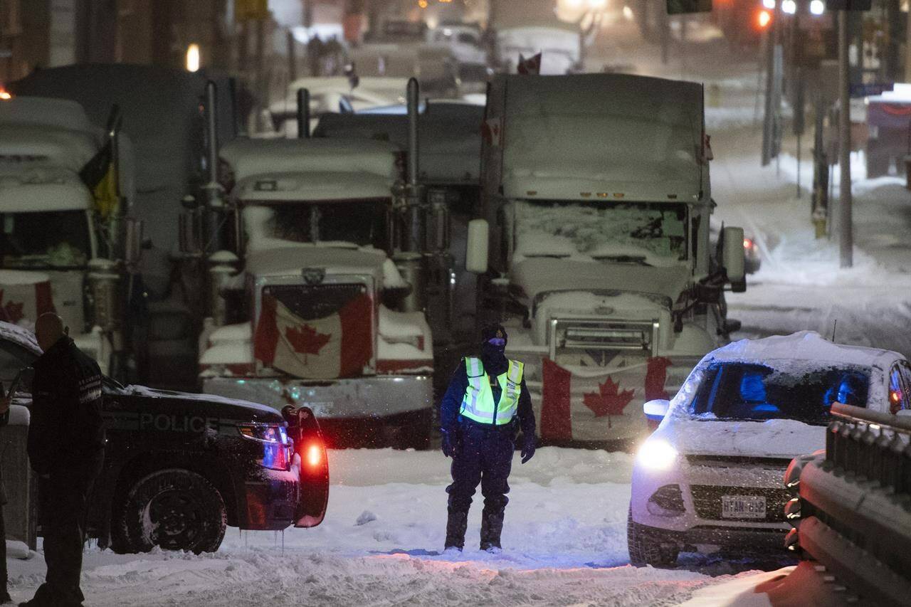 An Ontario Provincial Police officer mans a roadblock along Wellington Street, as a winter storm warning was in effect, on the 22nd day of a protest against COVID-19 measures that had grown into a broader anti-government protest in Ottawa on Friday, Feb. 18, 2022. THE CANADIAN PRESS/Justin Tang